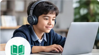 A learner wearing headphones takes notes while studying on a laptop at home.