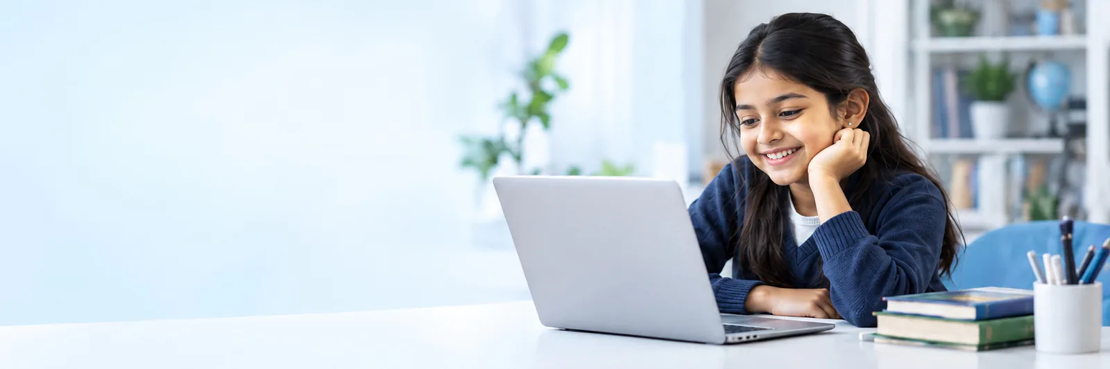 A school-age learner studying on a laptop in a bright learning space.